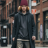 Man walking on an urban city street wearing a burgundy beanie with black embroidered Capricorn zodiac symbol
