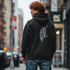 Person wearing a black hoodie with a tiger design on the back, standing on a city street.