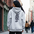 Person wearing a gray hoodie with a tiger design on the back, walking down a city street.